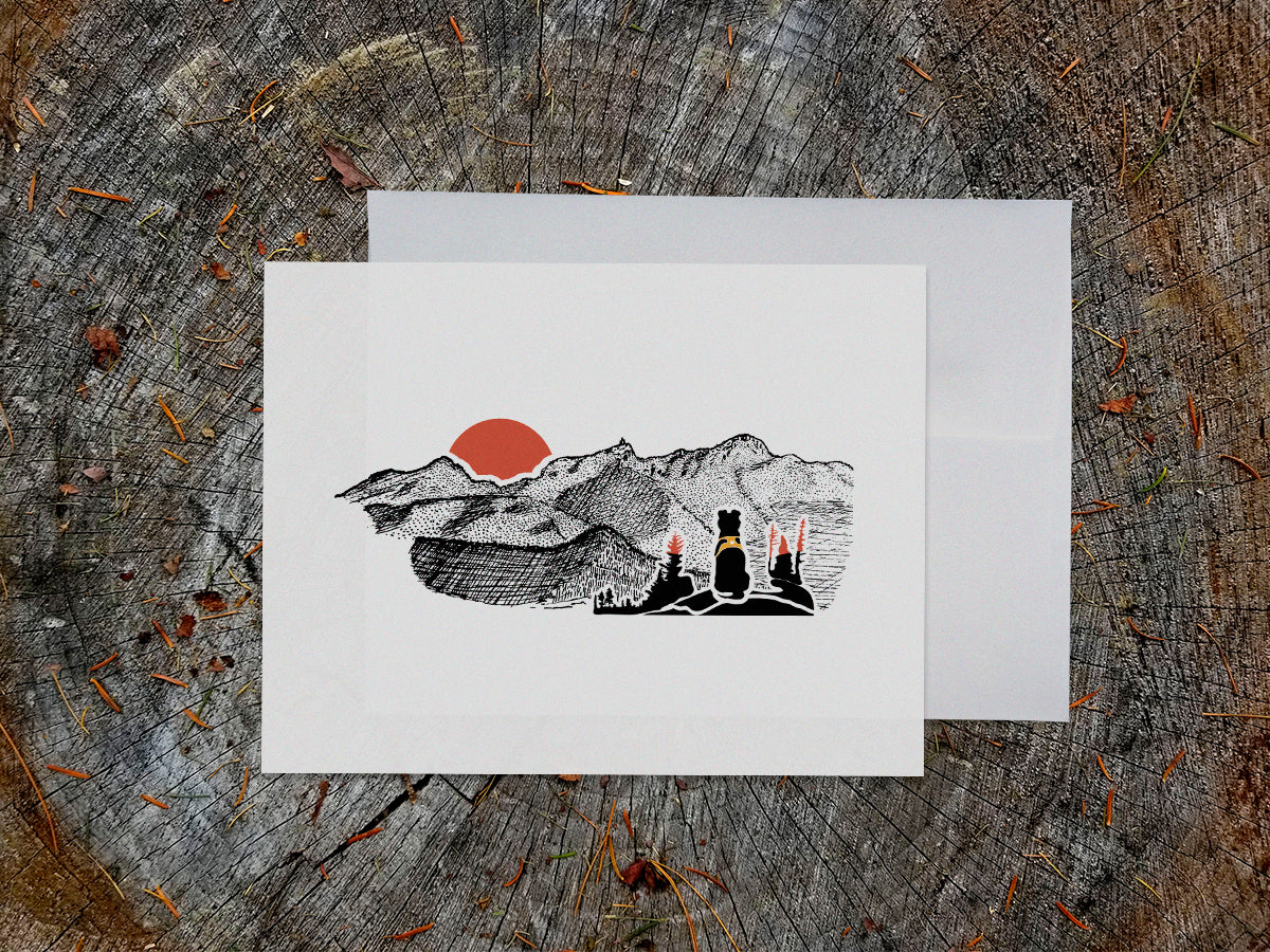Greeting card with image of black dog looking at a red sunset behind mountains.