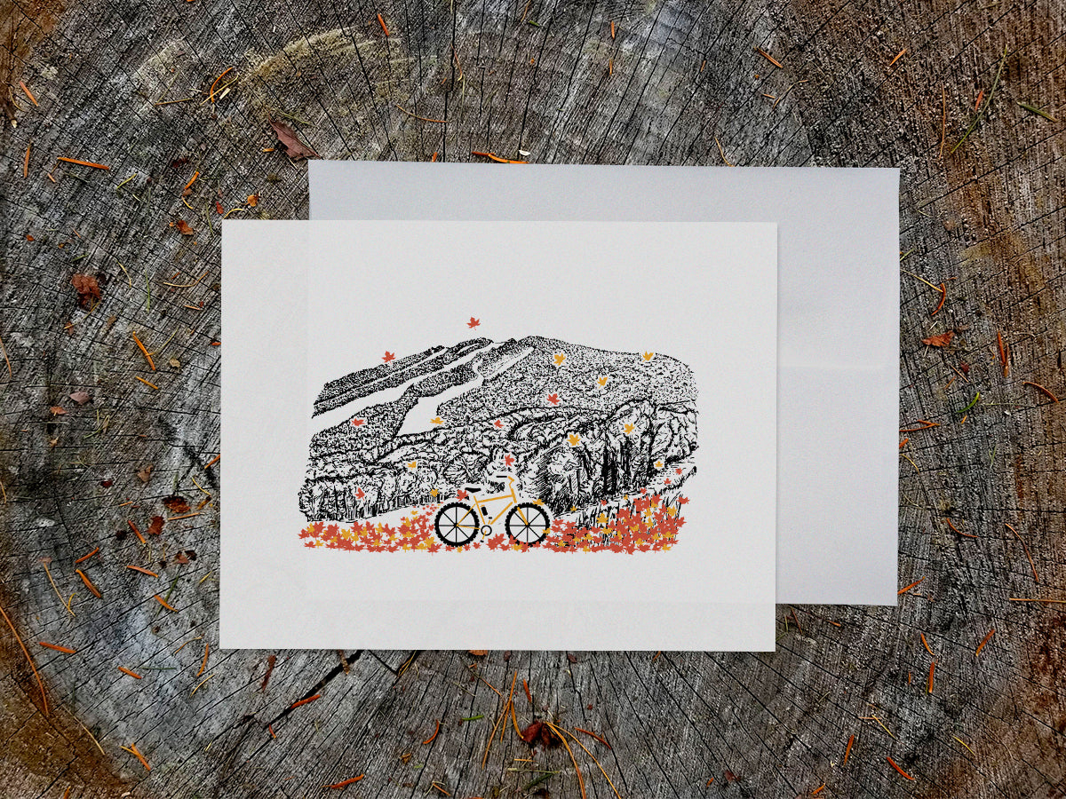 Greeting card with image of a mountain bike surrounded by brightly colored leaves with a  mountain in the background.