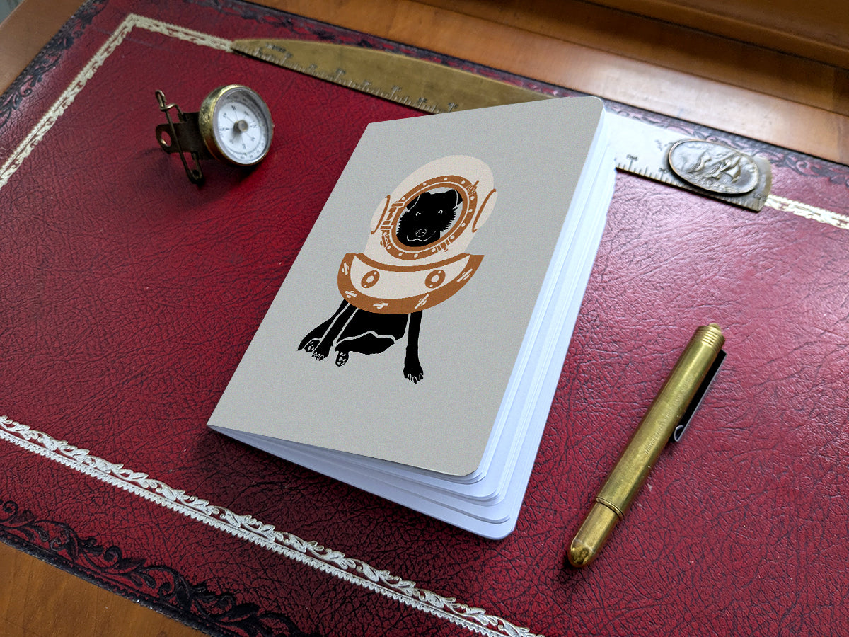 Notebook with illustration of a dog with scuba diving helmet on a red desk.
