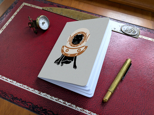 Notebook with illustration of a dog with scuba diving helmet on a red desk.