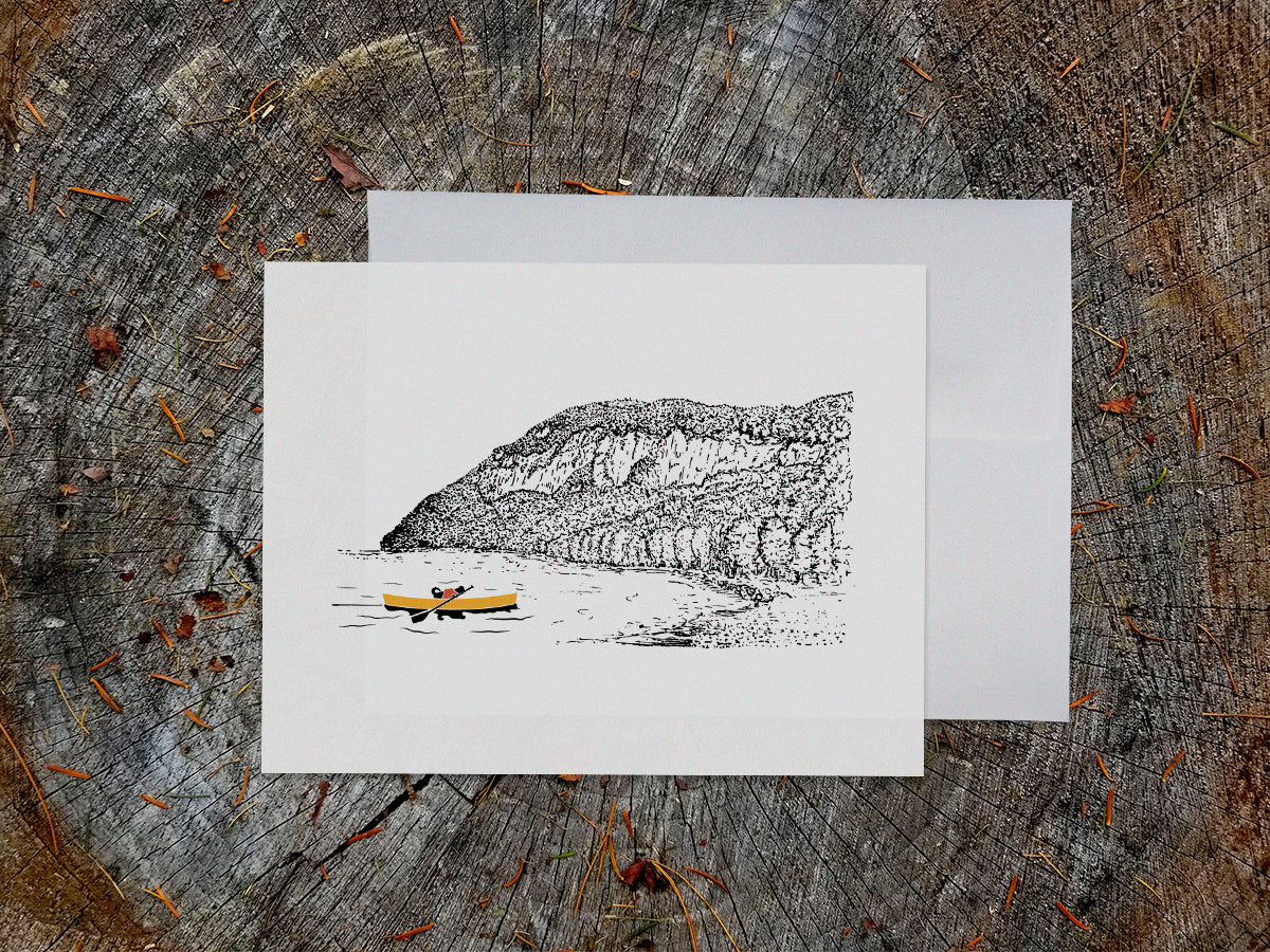 Greeting card featuring a dog paddling a canoe with mountain in the background.