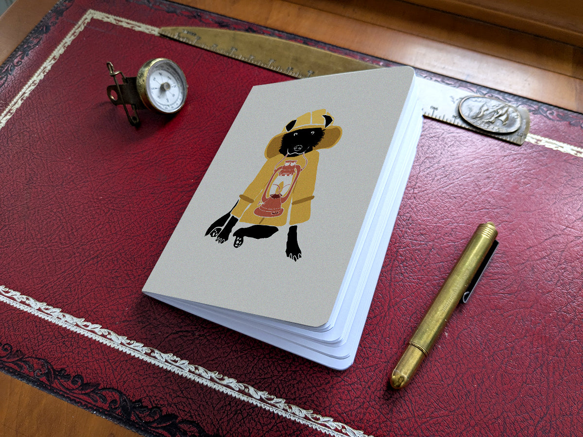 Notebook with illustration of a dog in fisherman yellow jacket with lamp on a red desk.