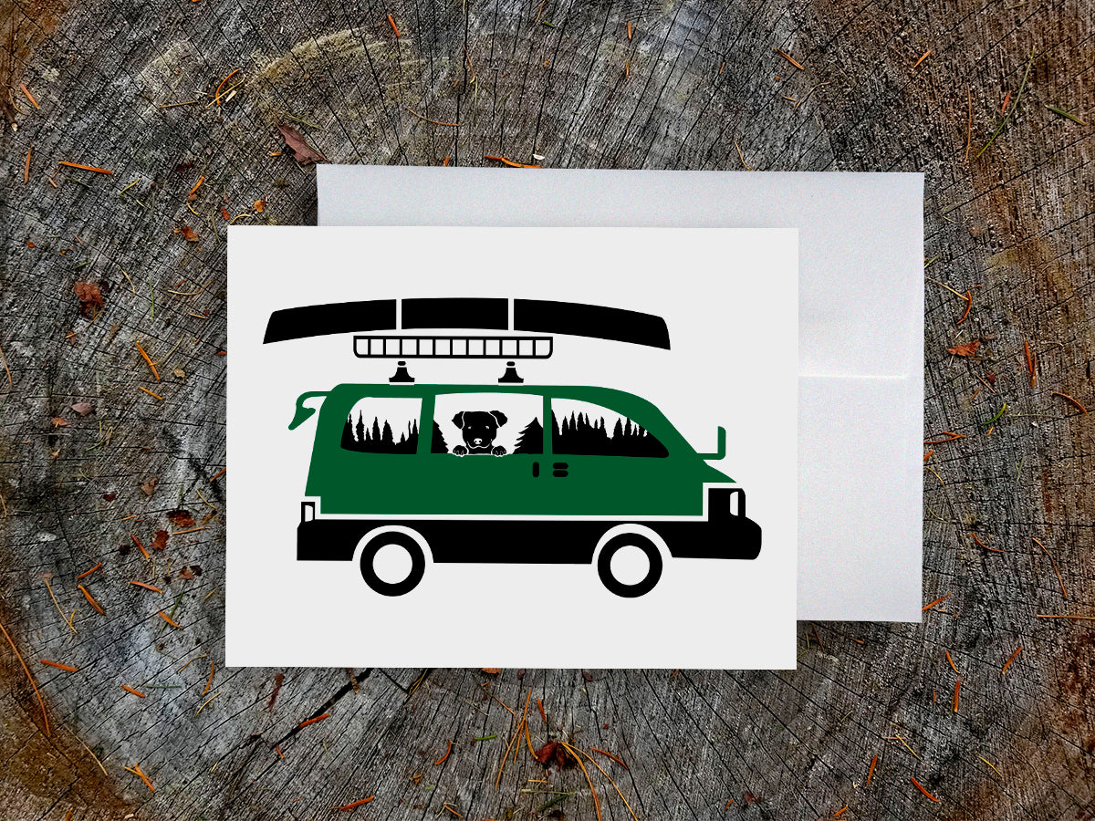 Greeting card with image of dog riding in a camper van with canoe on top.