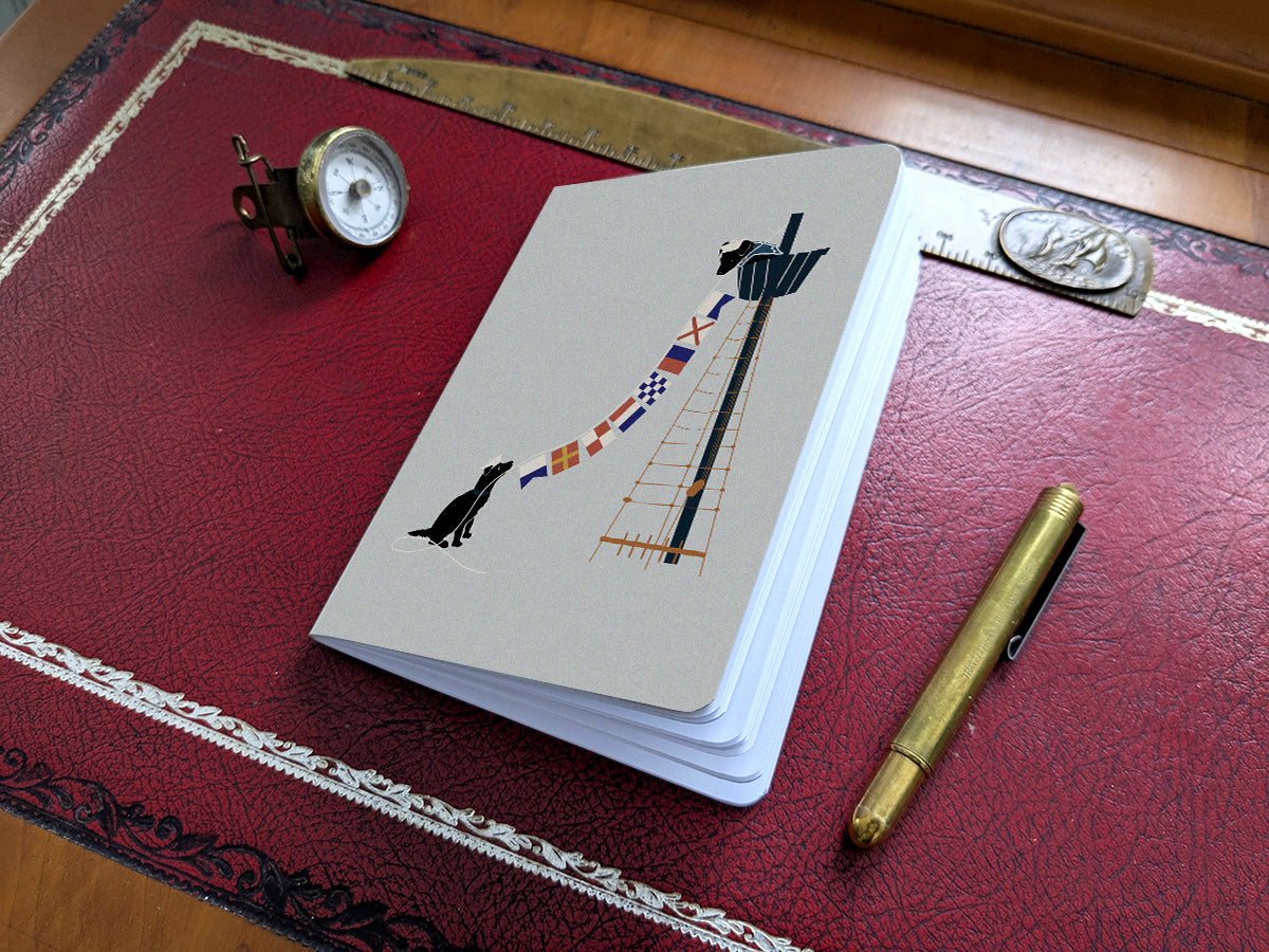 Notebook with illustration of a dogs hanging nautical flags on a red desk.