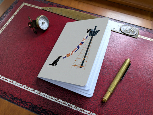Notebook with illustration of a dogs hanging nautical flags on a red desk.