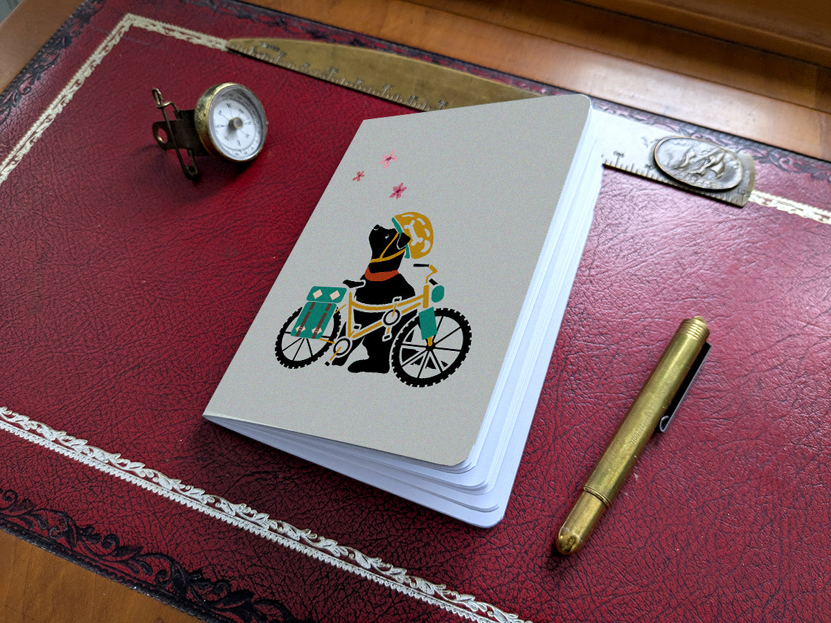 Notebook with illustration of a dog with helmet and bike on a red desk.