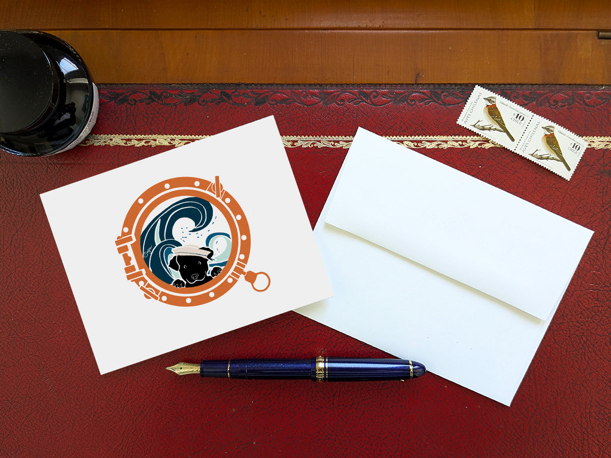 Greeting card with image of a dog looking through a porthole on a table with a blue pen and envelope and stamps.