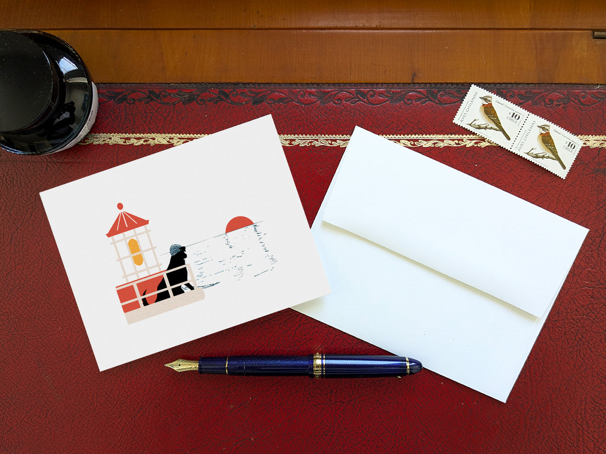 Greeting card with image of a dog in a lighthouse on a table with a blue pen and envelope and stamps.