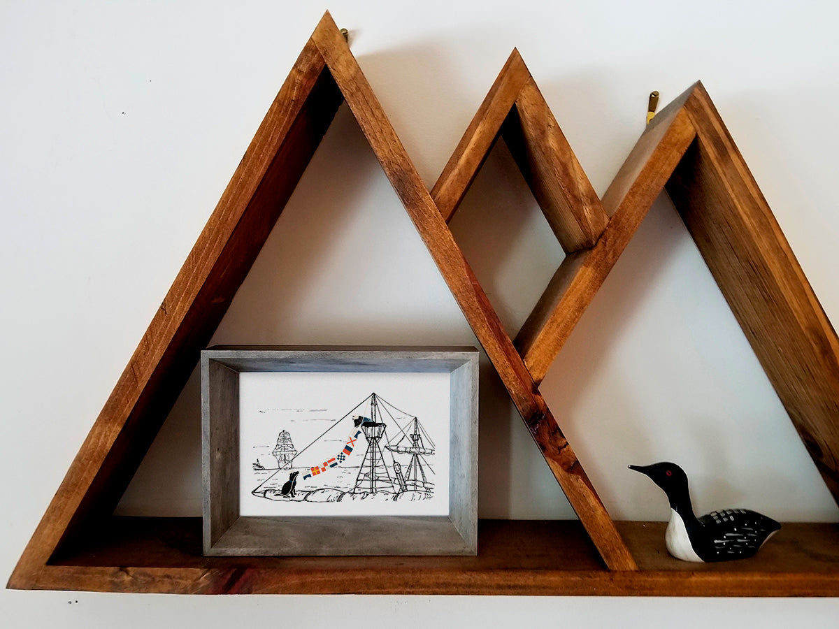 Framed art print with illustration of two dogs hanging nautical flags on a ship placed on a wooden shelf.
