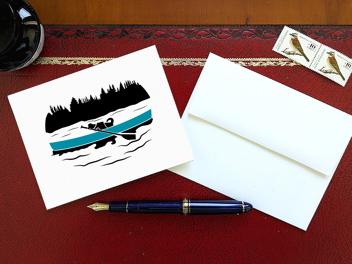 Greeting card with a black dog paddling a blue canoe on a table with a blue pen and envelope and stamps