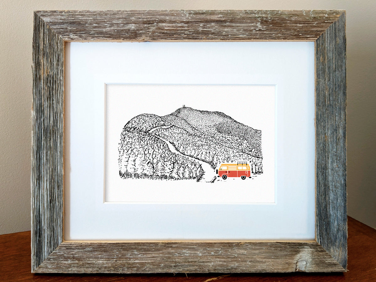 Framed art print of red and yellow van at the bottom of a mountain road.