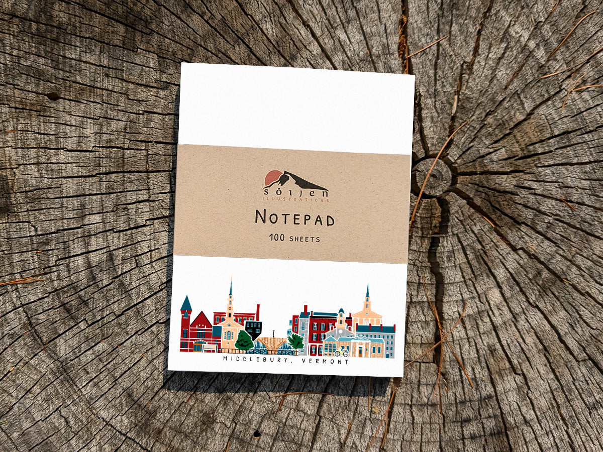 Notepad with illustration of Middlebury, Vermont buildings in skyline on a wood surface