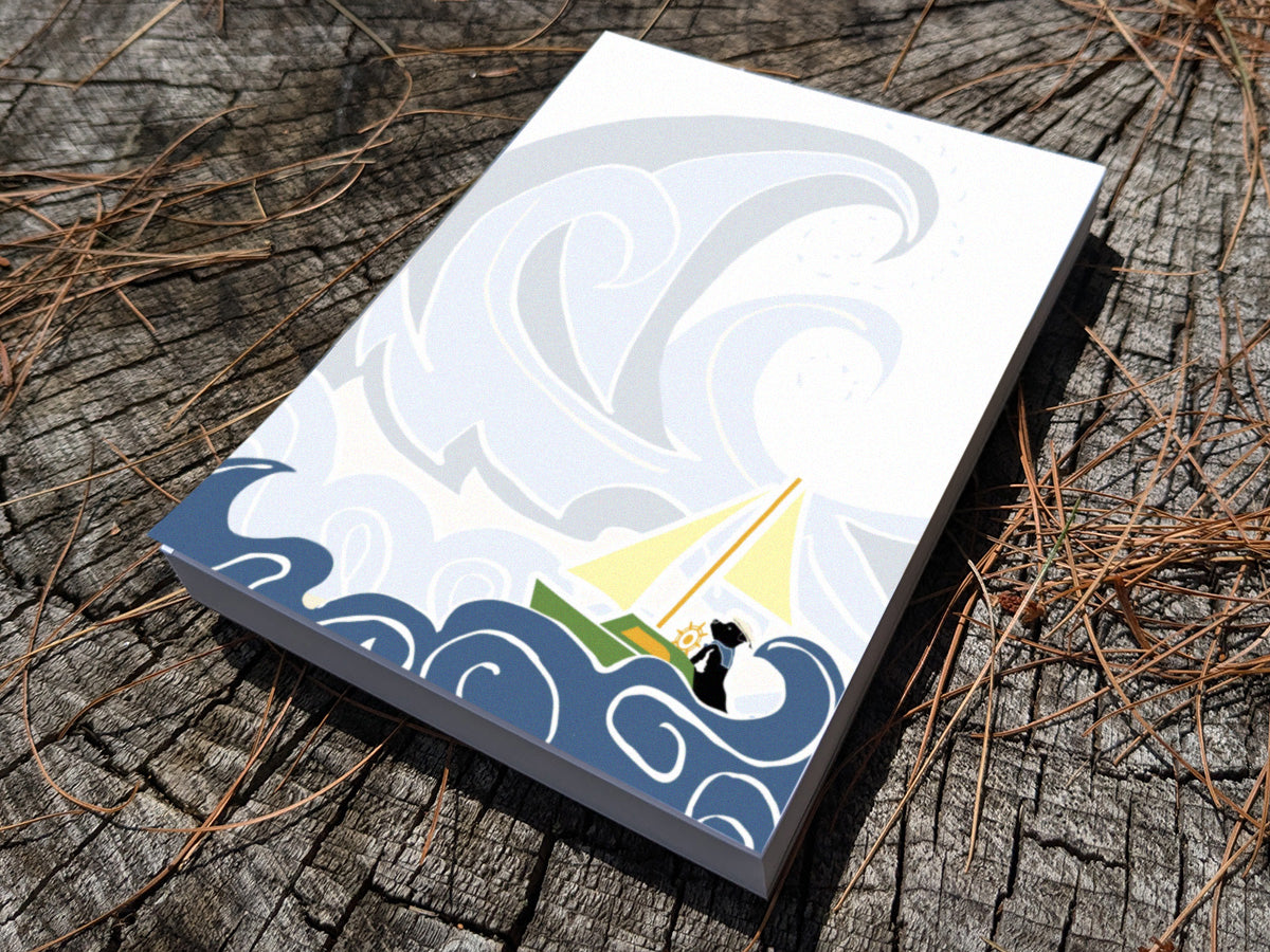 Notepad with illustration of dog sailing big waves on a wood surface.