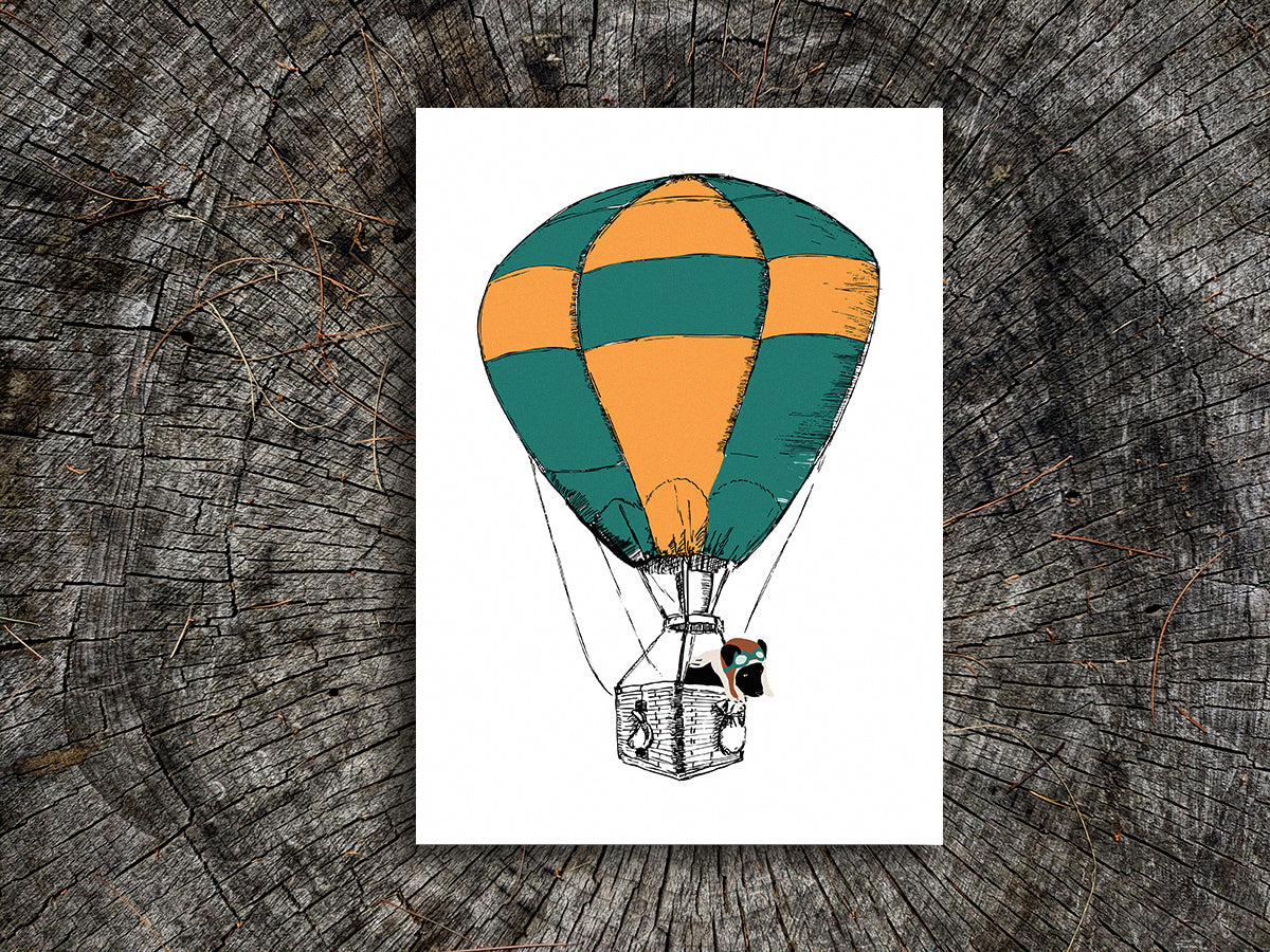 Illustration with a green and yellow hot air balloon with a black dog inside the basket on a wooden background.