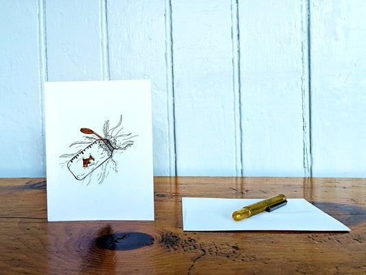 White card with a black ink drawing of a water bottle with red fish on a wooden surface with a pen and envelope.