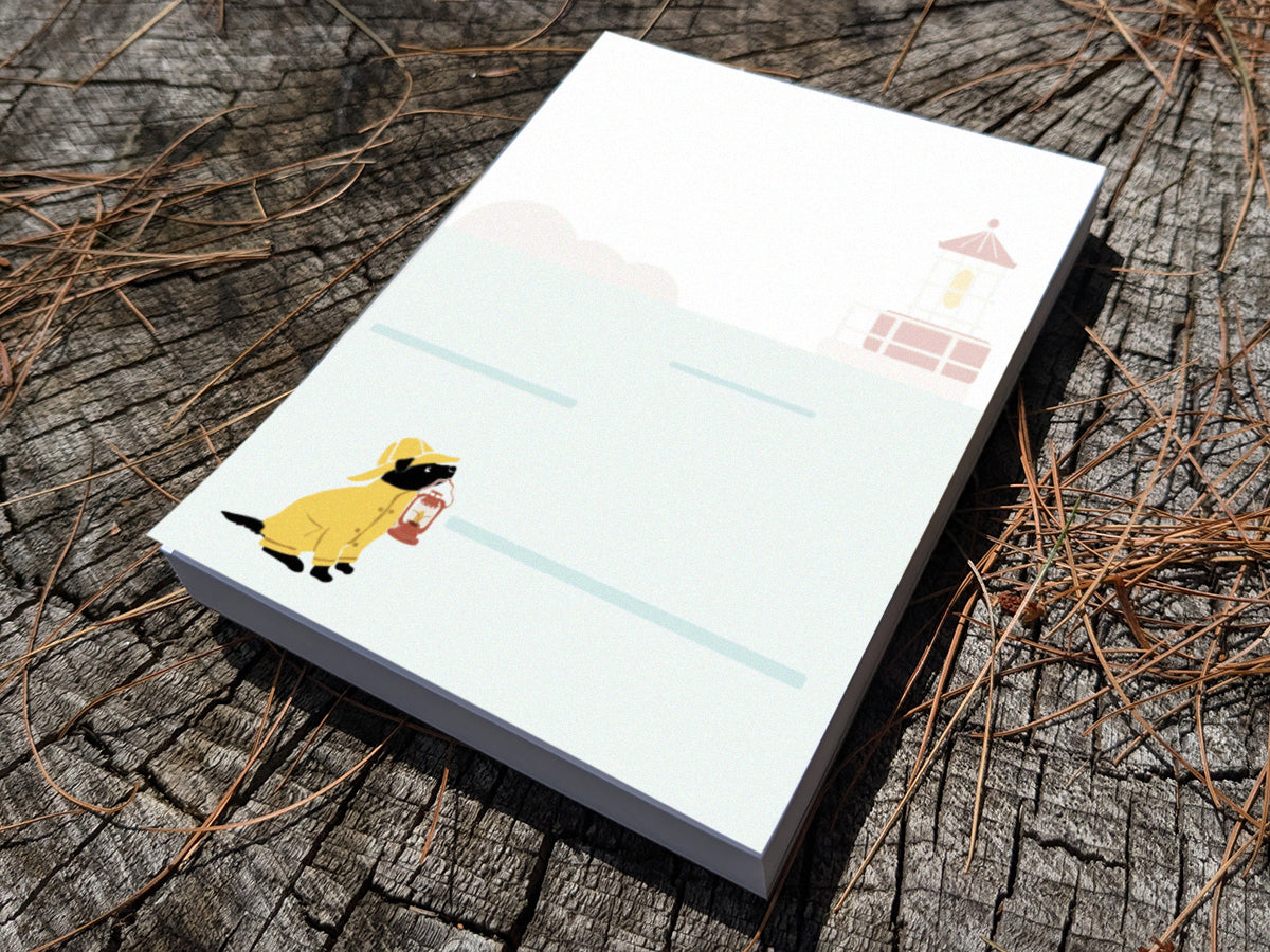 Notepad with an illustration of a dog in yellow hat and jacket holding a red lantern on a wood surface.
