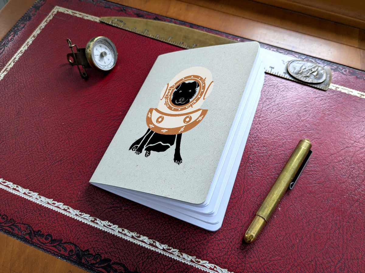 Notebook with dog with a diving helmet with a pen and small compass.