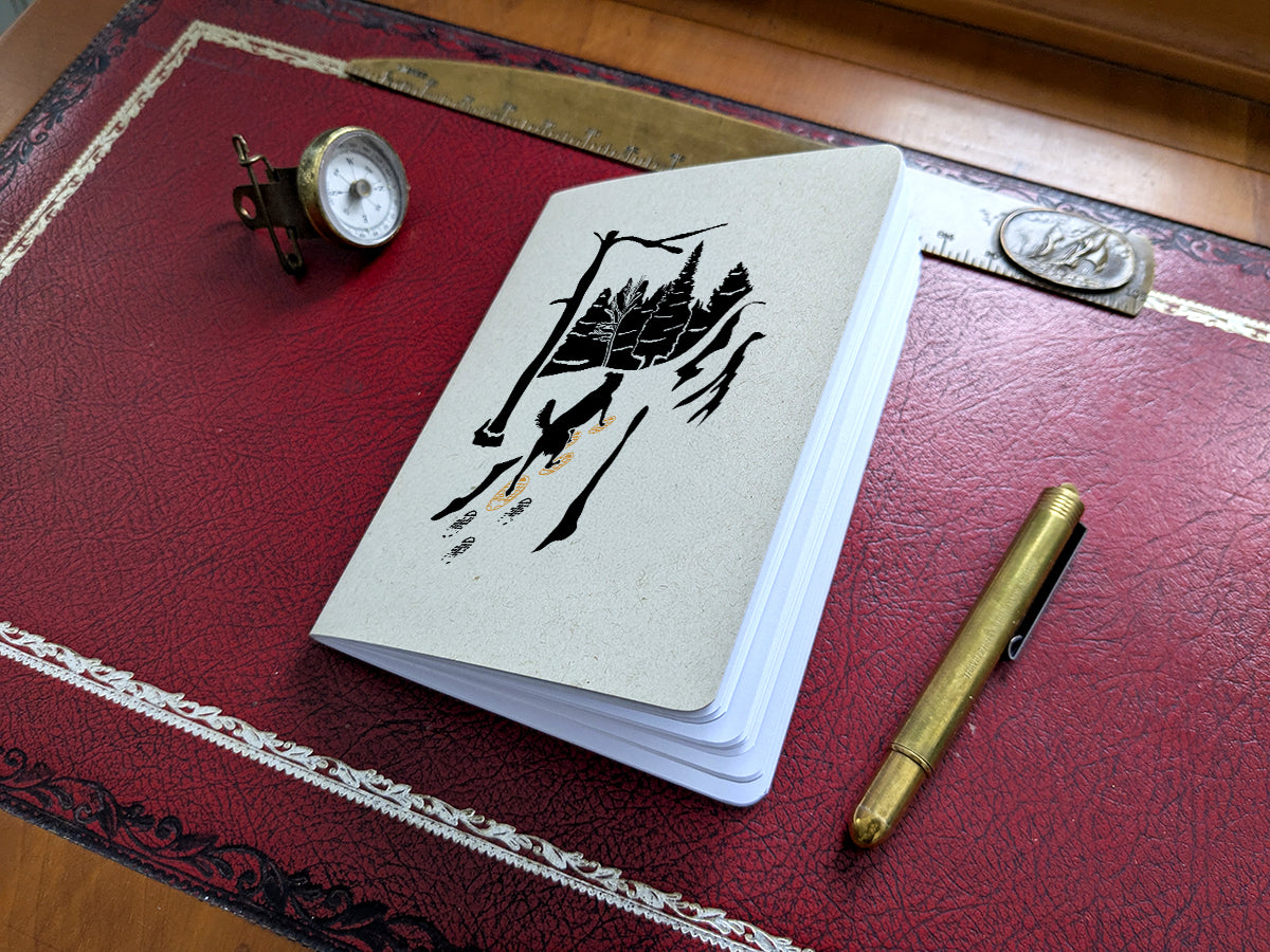 Notebook with dog snowshoeing illustration on a red surface with a pen and small compass.