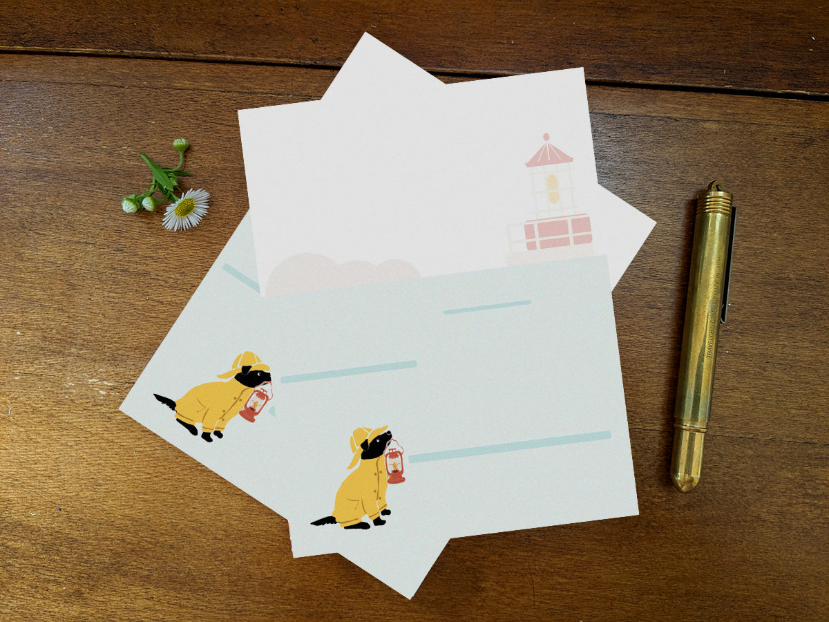 Notepad with an illustration of a dog in yellow hat and jacket holding a red lantern on a wood surface and gold pen.