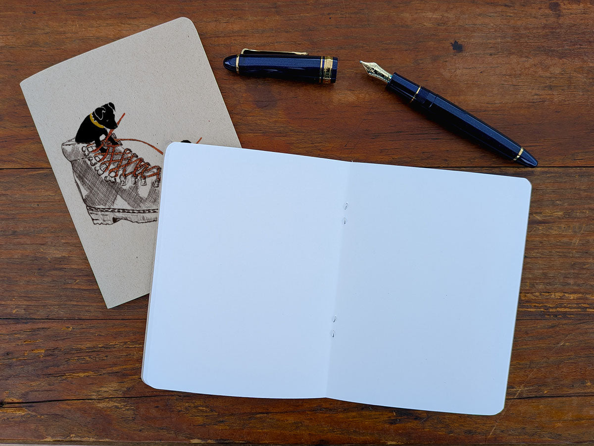 Open blank notebook with a pen and a pen on a wooden surface