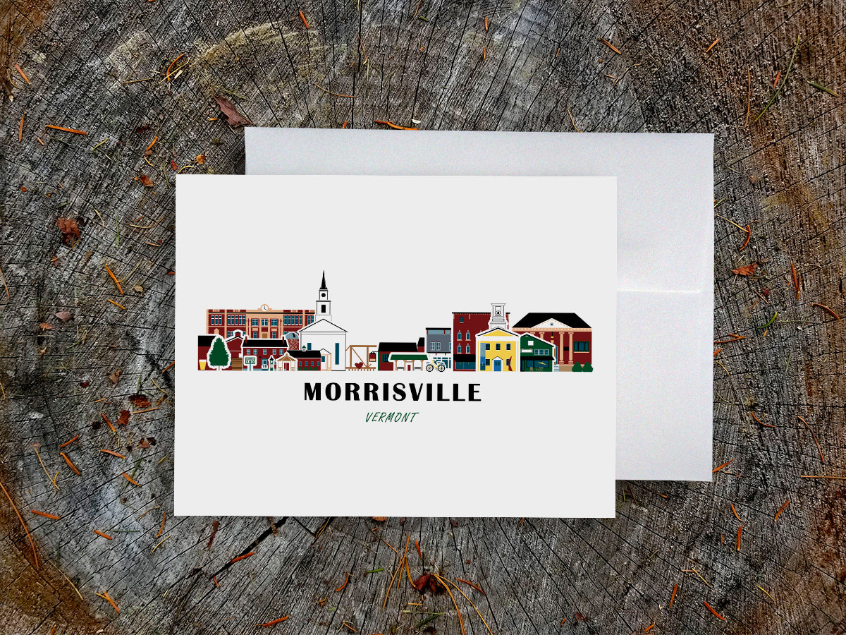 Greeting card with image of buildings arranged in a city skyline with the text Morrisville Vermont on a table with envelope.