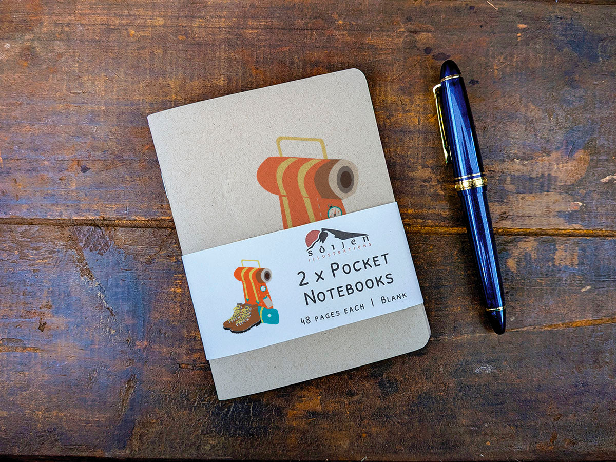 Two pocket notebooks with a pen on a wooden surface