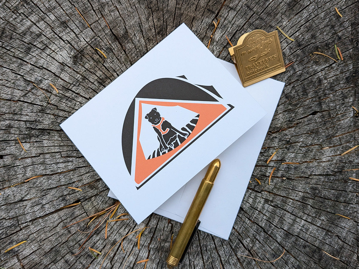 Greeting card with dog sitting in an orange tent.