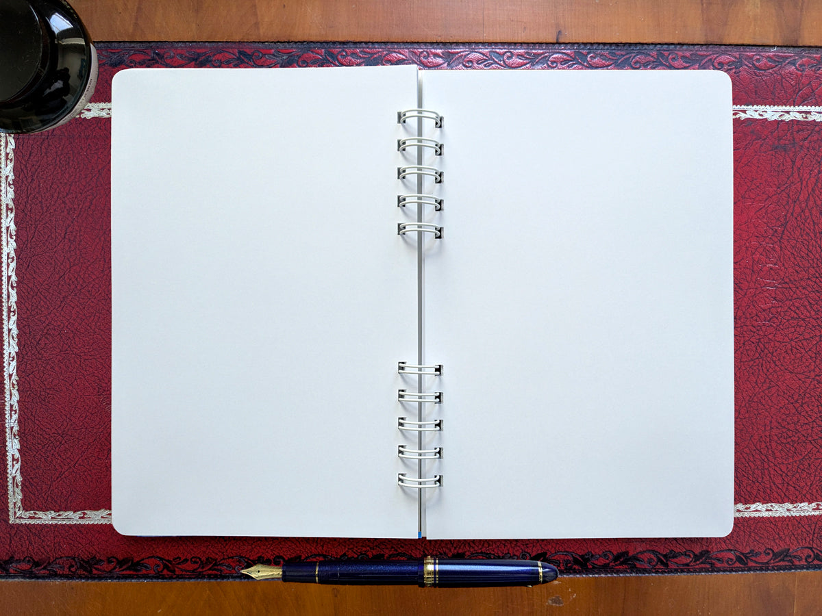 Open blank notebook with a pen on a decorative surface
