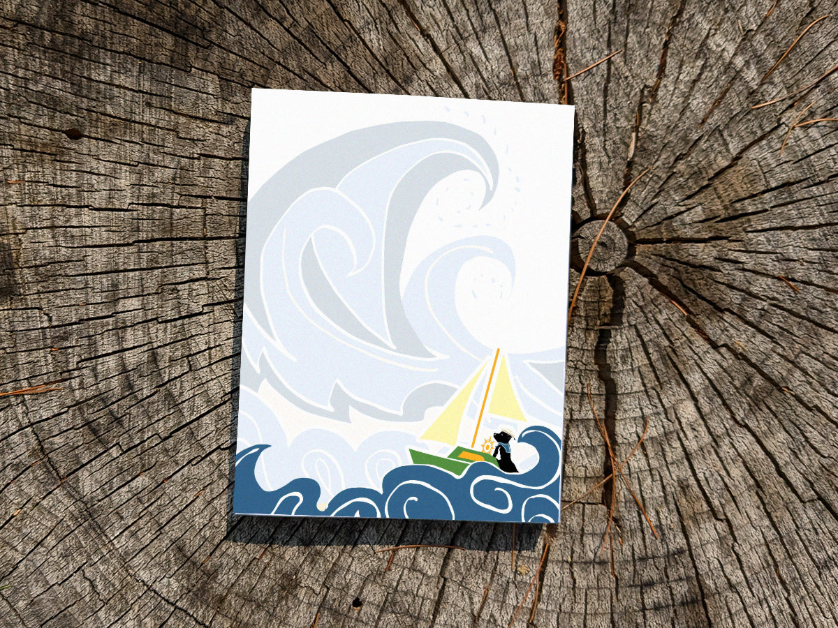 Notepad with illustration of dog sailing big waves on a wood surface.