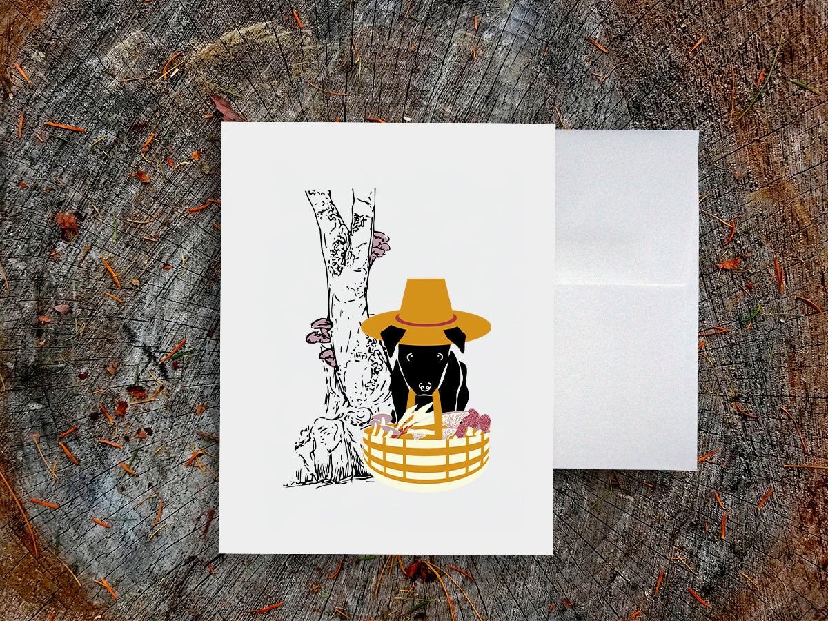 White card with drawing of dog holding basket with mushrooms on a wooden surface.