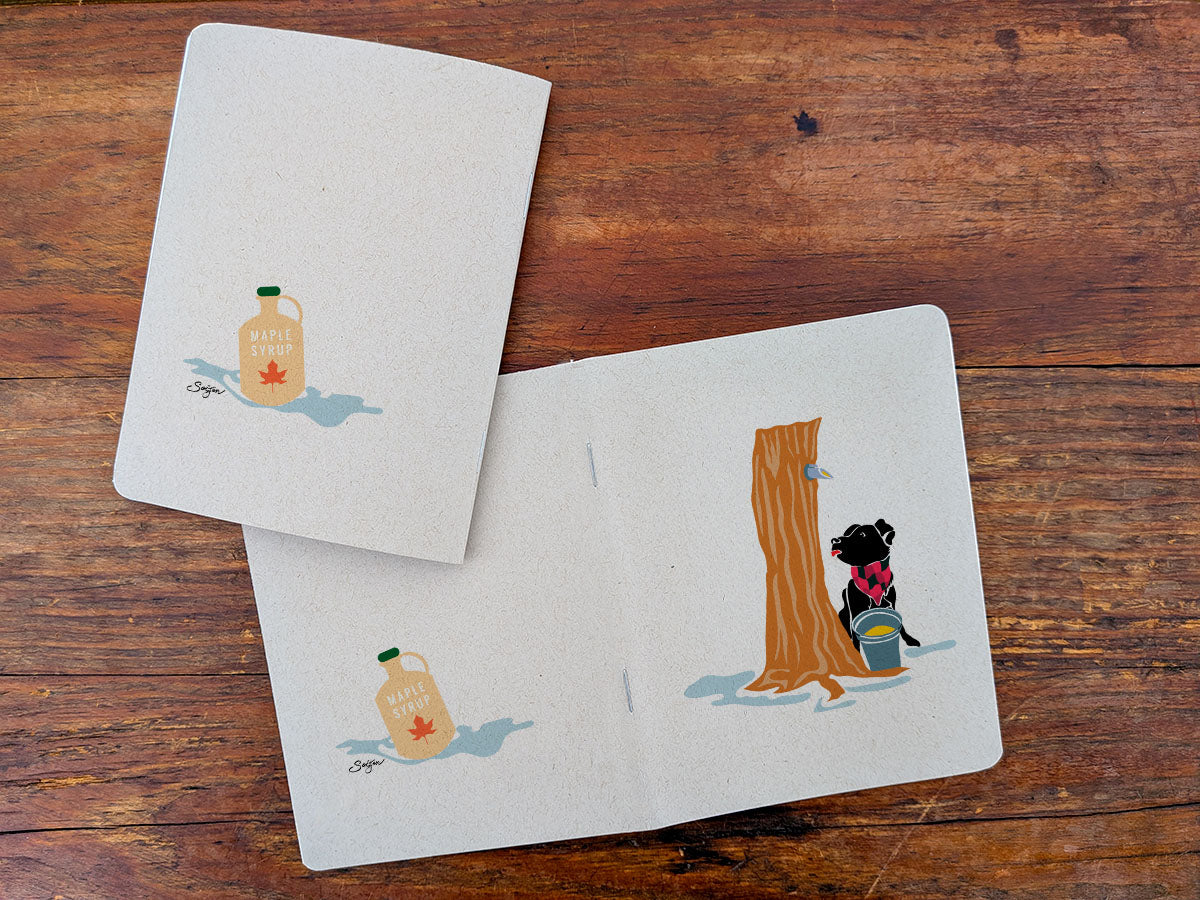 Two notebooks with dog maple surgaring illustration on a wooden surface