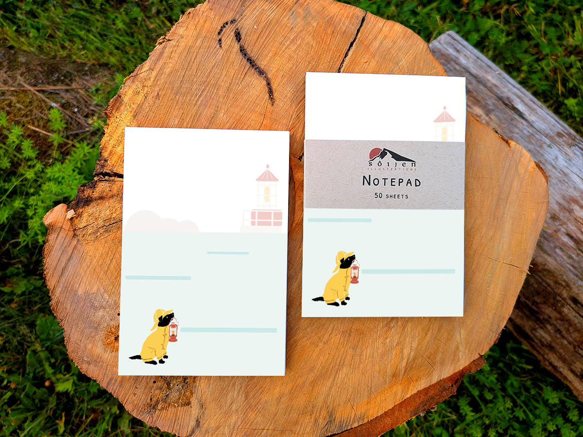 Two notepads with an illustration of a dog in yellow hat and jacket holding a red lantern with a lighthouse in the background, placed on a wood surface.
