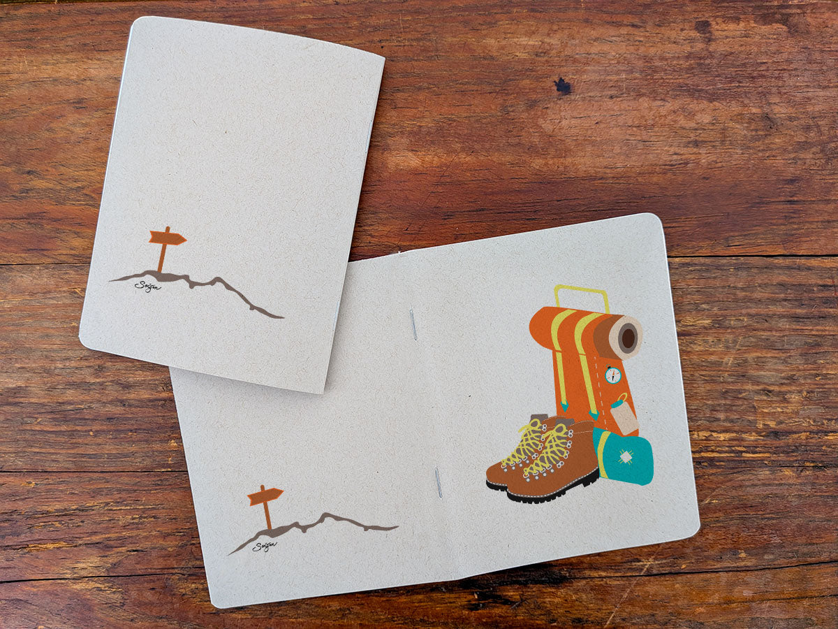 Two notebooks with hiking boot and backpack illustration on a wooden surface