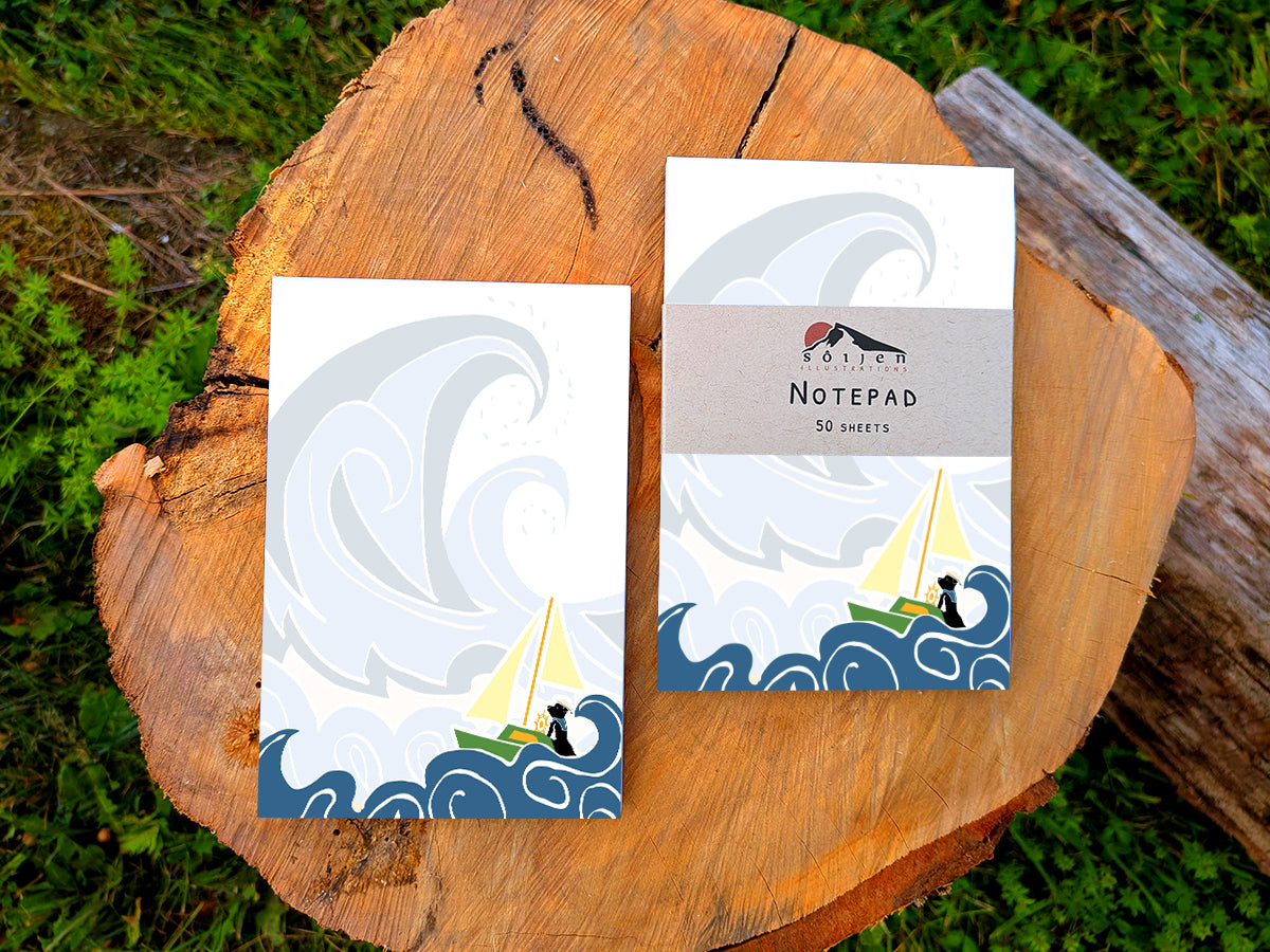 Two notepads with illustration of dog sailing big waves on a wood surface.