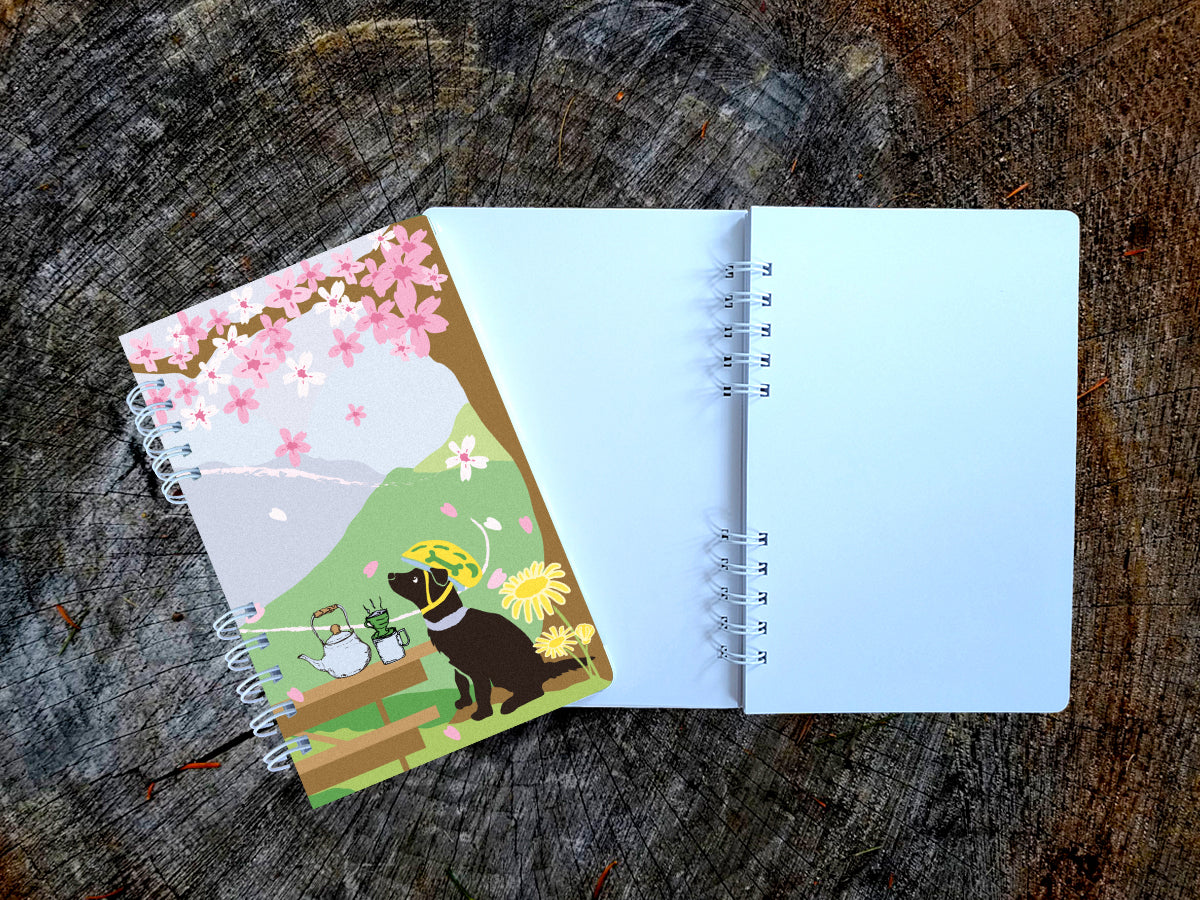 Open notebook with a colorful cover featuring a dog with helmet and cherry blossoms on a wooden surface.
