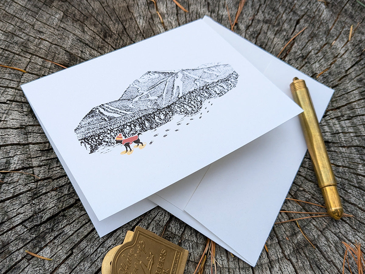 Greeting card with image of a mountain with ski trails and dog snowshoeing.