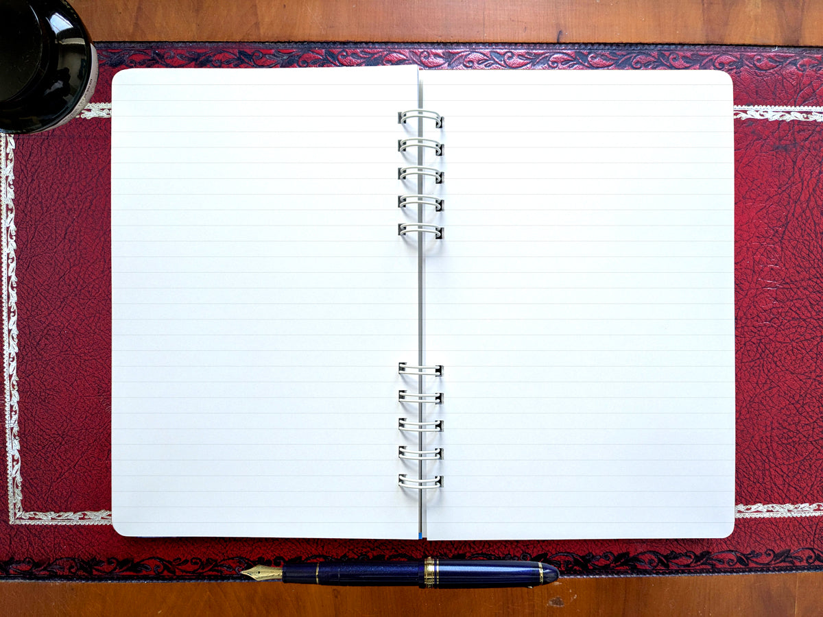 Open lined notebook with a pen on a red textured surface